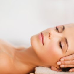 spa, resort, beauty and health concept - beautiful woman in spa salon getting face treatment