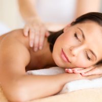 health, beauty, resort and relaxation concept - beautiful woman with closed eyes in spa salon getting massage